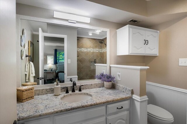 full bathroom with wainscoting, a shower stall, toilet, vanity, and visible vents