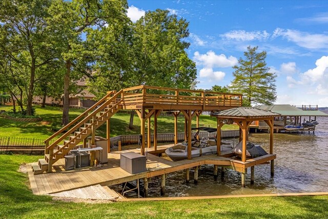 exterior space featuring boat lift, fence, a water view, and a yard