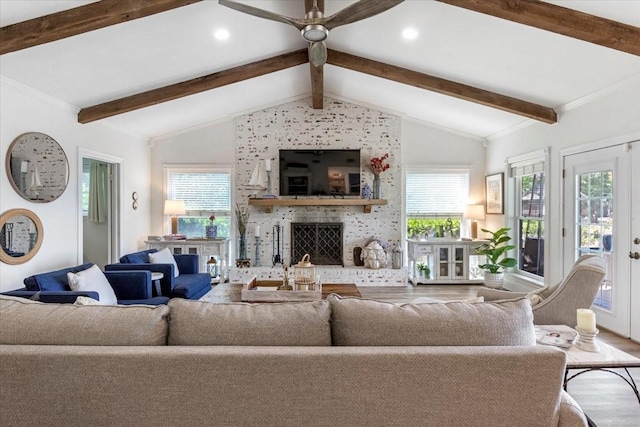 living area featuring wood finished floors, a healthy amount of sunlight, lofted ceiling with beams, ceiling fan, and a fireplace