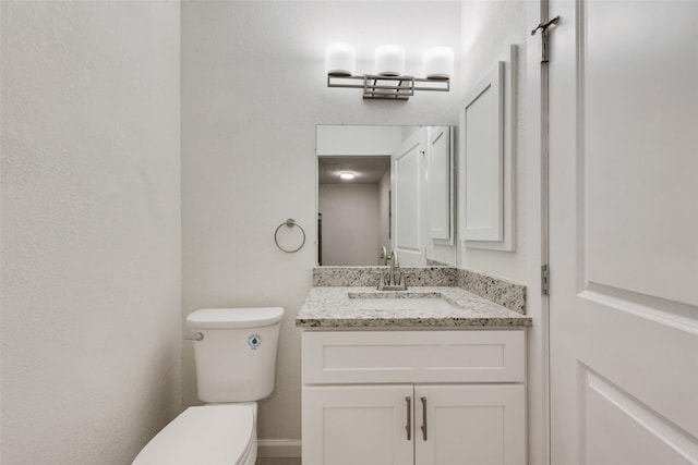 bathroom featuring toilet, vanity, and baseboards