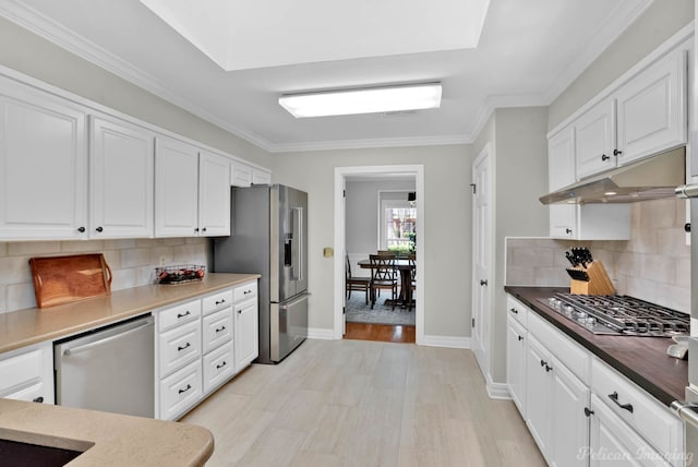 kitchen with appliances with stainless steel finishes, white cabinetry, tasteful backsplash, and ornamental molding
