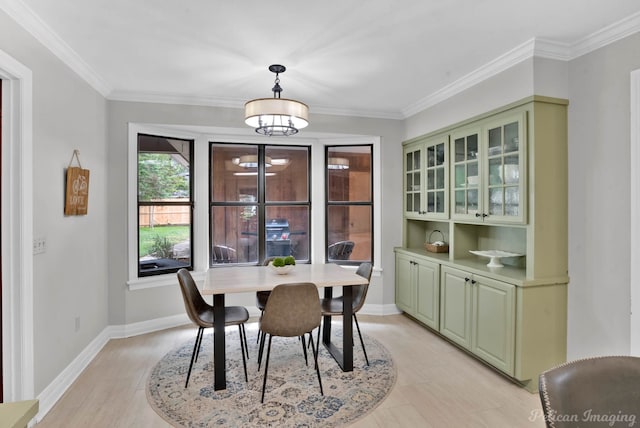 dining area with crown molding, light wood-style floors, and baseboards