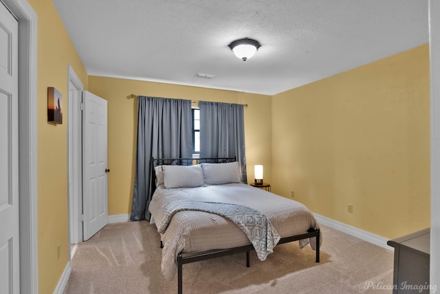 bedroom with light colored carpet, baseboards, and a textured ceiling