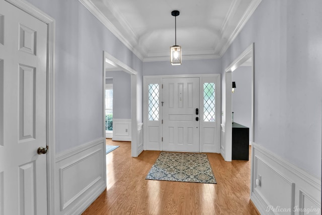 foyer featuring a decorative wall, wainscoting, crown molding, and light wood finished floors