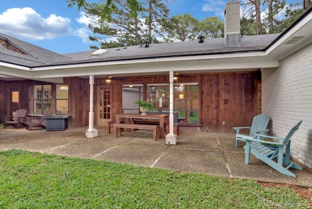 rear view of house featuring a patio, a chimney, and a shingled roof