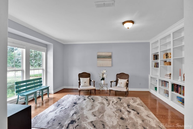 living area featuring crown molding, baseboards, built in features, and wood finished floors