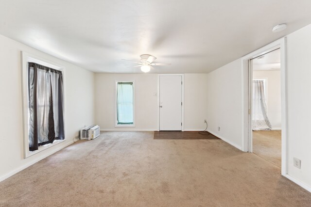 unfurnished room with light colored carpet, a ceiling fan, and baseboards