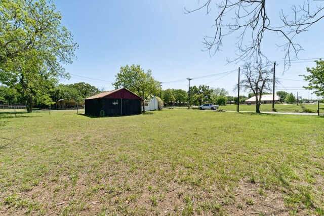 view of yard with fence, a pole building, and an outbuilding