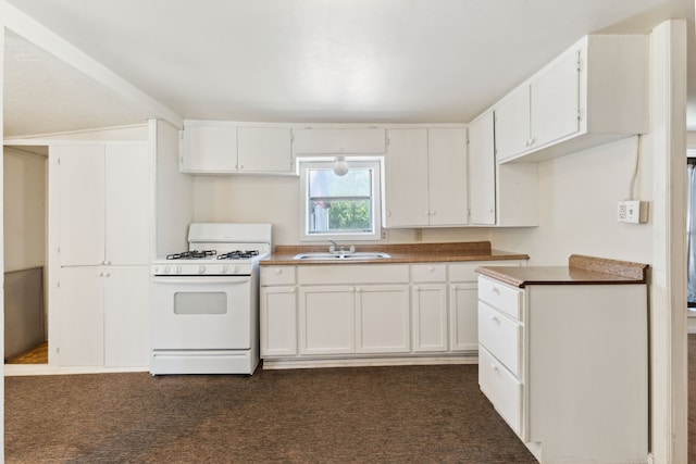 kitchen with gas range gas stove, dark colored carpet, white cabinetry, and a sink