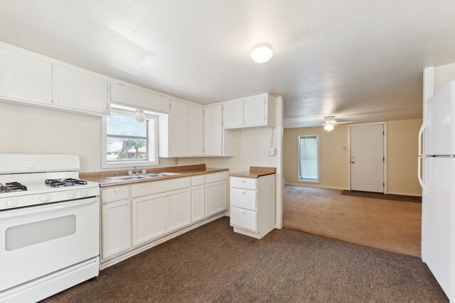 kitchen with dark colored carpet, white cabinetry, white appliances, and a sink