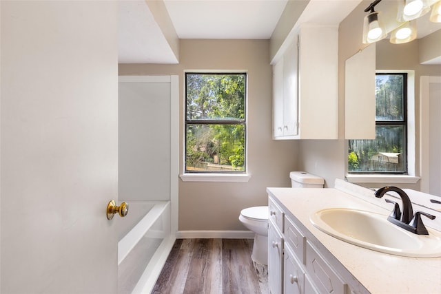 2820 Bois D Arc St, Commerce, TX 75428 - full bathroom featuring toilet, vanity, baseboards, a bath, and wood finished floors