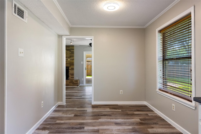 2820 Bois D Arc St, Commerce, TX 75428 - spare room featuring a textured ceiling, dark wood finished floors, ceiling fan, crown molding, and baseboards