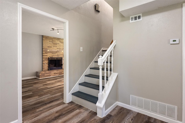 2820 Bois D Arc St, Commerce, TX 75428 - staircase with wood finished floors, a fireplace, baseboards, and rail lighting
