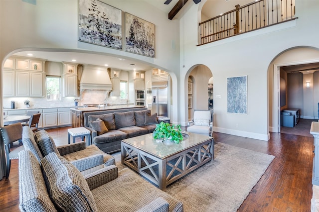 living room with arched walkways, a high ceiling, and wood finished floors