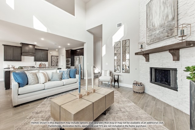 living area with baseboards, visible vents, wood finish floors, and a high ceiling