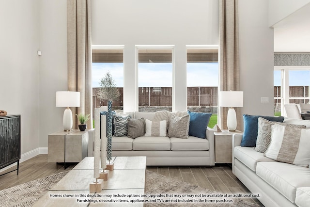 living area with a towering ceiling, wood finish floors, and baseboards
