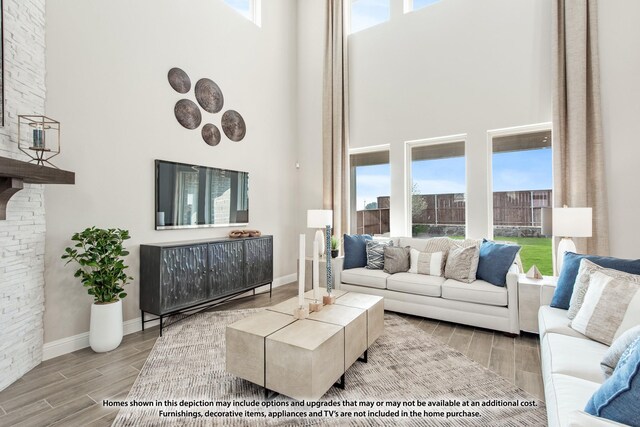 living room featuring wood tiled floor, a high ceiling, baseboards, and plenty of natural light