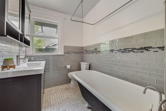 123 S Rosemont Ave, Dallas, TX 75208 - bathroom featuring a freestanding bath, vanity, toilet, tile patterned floors, and tile walls