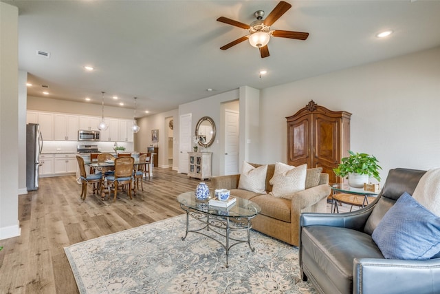 living room featuring recessed lighting, a ceiling fan, visible vents, and light wood-style flooring