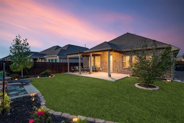 rear view of house with brick siding, a fenced backyard, a yard, and a patio area