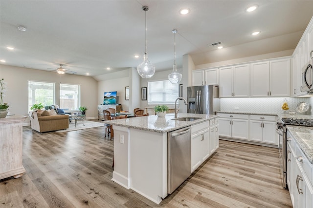 kitchen featuring light stone counters, stainless steel appliances, ceiling fan, a sink, and open floor plan