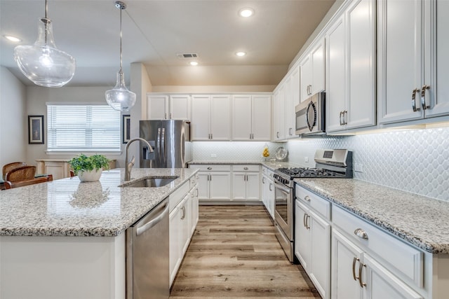 kitchen featuring a sink, white cabinets, stainless steel appliances, and light wood-type flooring
