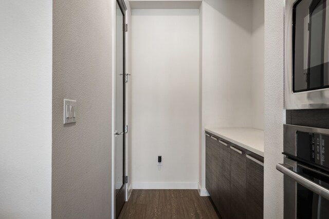 corridor featuring dark wood finished floors and baseboards