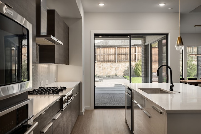 kitchen with light countertops, modern cabinets, wall chimney range hood, and a sink