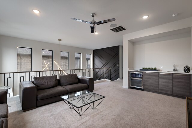 living area featuring light colored carpet, visible vents, ceiling fan, beverage cooler, and bar area