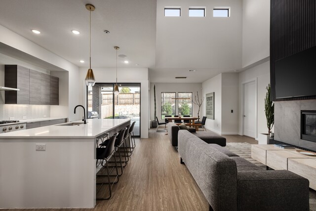 living room featuring baseboards, recessed lighting, light wood-style flooring, and a towering ceiling