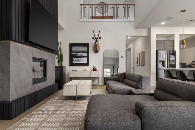 living area with a tile fireplace, wood finished floors, and a high ceiling