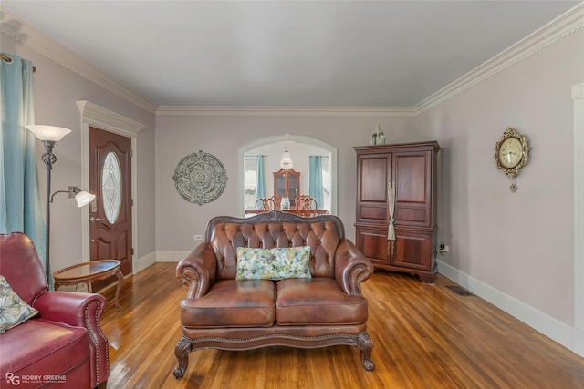 living area with crown molding, baseboards, visible vents, and wood finished floors
