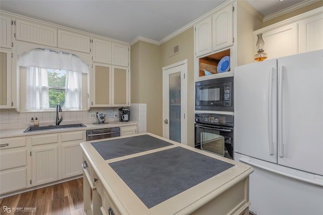 kitchen featuring crown molding, a sink, tasteful backsplash, visible vents, and black appliances