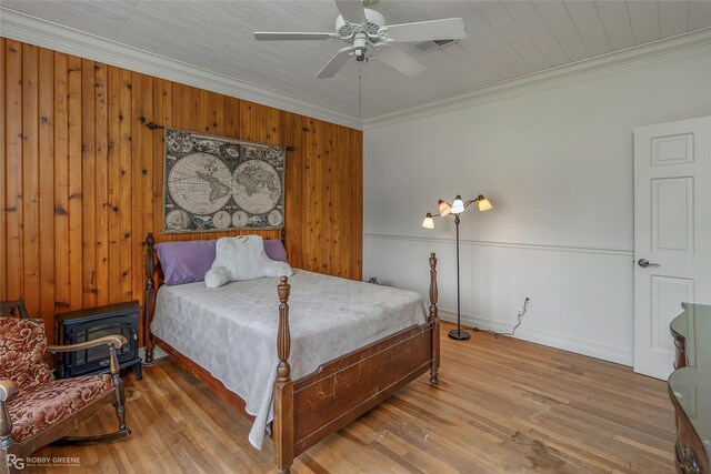 bedroom with visible vents, ornamental molding, wood finished floors, baseboards, and wooden walls