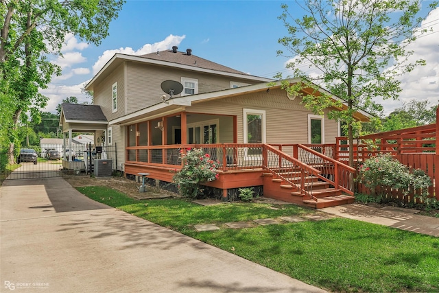 back of property with a lawn, a wooden deck, a gate, fence, and cooling unit