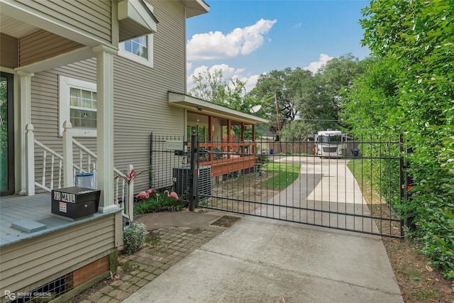 view of gate with fence and central air condition unit