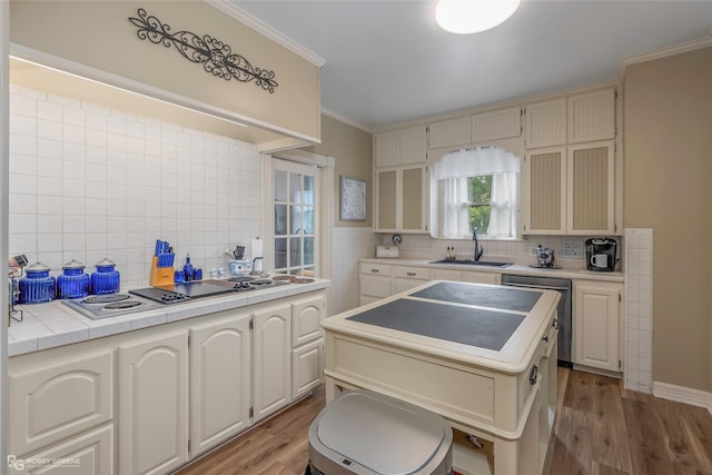 kitchen featuring crown molding, stainless steel dishwasher, a sink, and tasteful backsplash