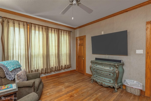 living room with crown molding, a ceiling fan, and hardwood / wood-style floors