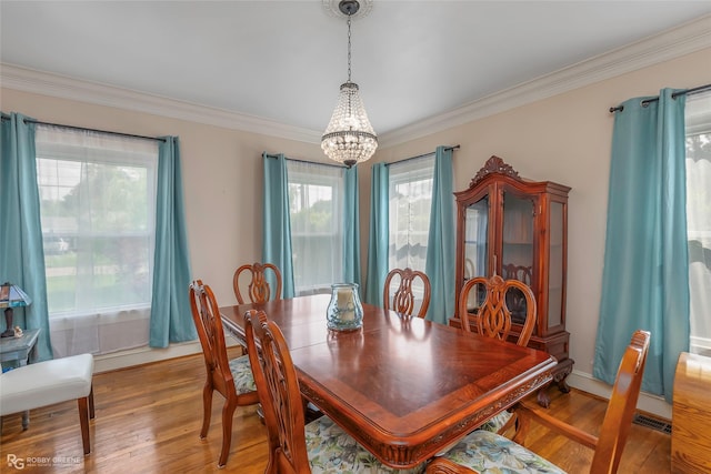 dining area featuring an inviting chandelier, crown molding, visible vents, and light wood-type flooring