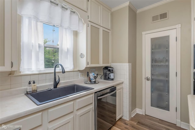 kitchen with decorative backsplash, visible vents, dishwasher, a sink, and ornamental molding