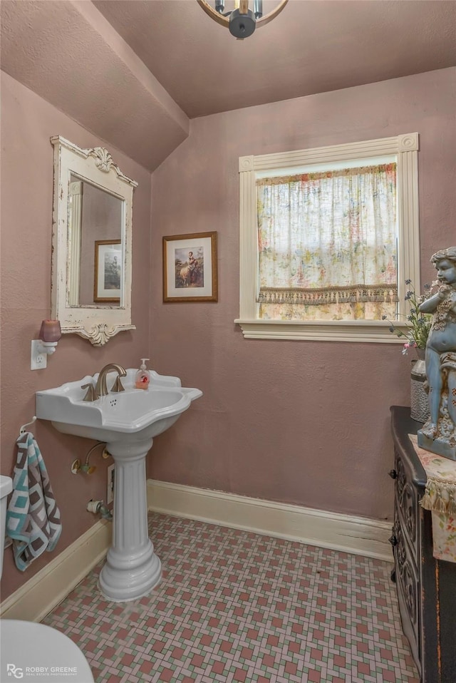 bathroom with toilet, tile patterned floors, baseboards, and lofted ceiling