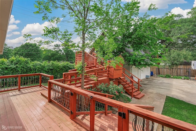 wooden terrace with stairway, fence, and a garage