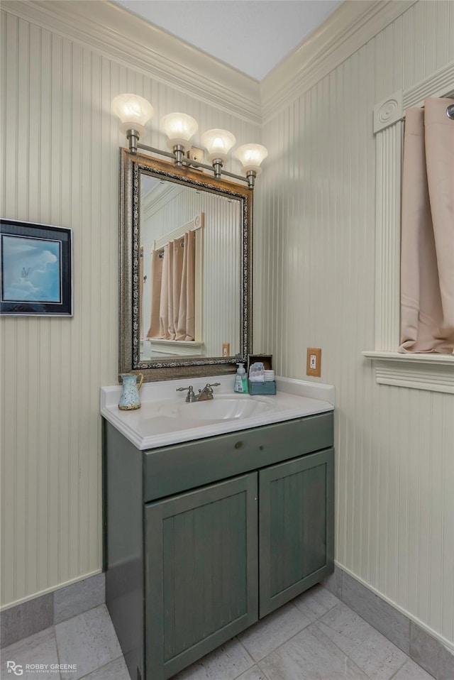 bathroom with crown molding, baseboards, tile patterned flooring, and vanity