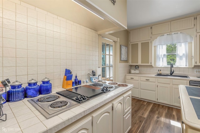 kitchen featuring dark wood-style floors, tile counters, tasteful backsplash, stovetop with downdraft, and a sink