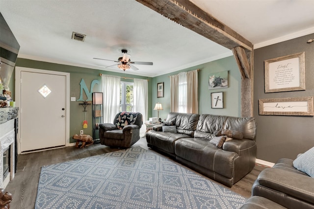 living area featuring a ceiling fan, visible vents, ornamental molding, and wood finished floors