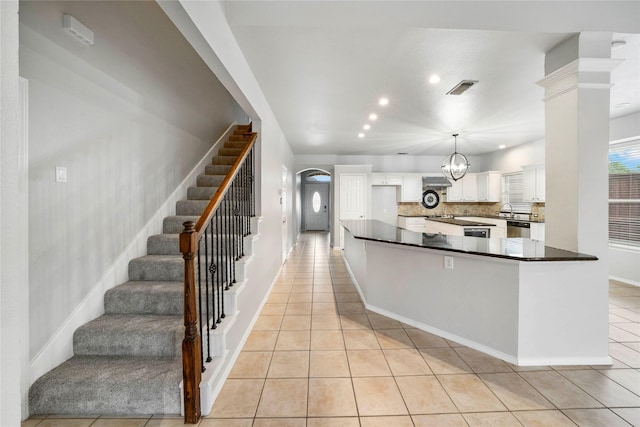 kitchen featuring white cabinets, light tile patterned flooring, dark countertops, backsplash, and visible vents