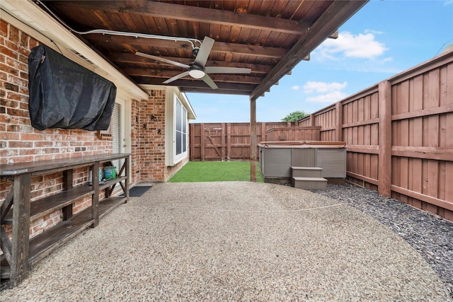 view of patio / terrace with a fenced backyard, ceiling fan, and a hot tub
