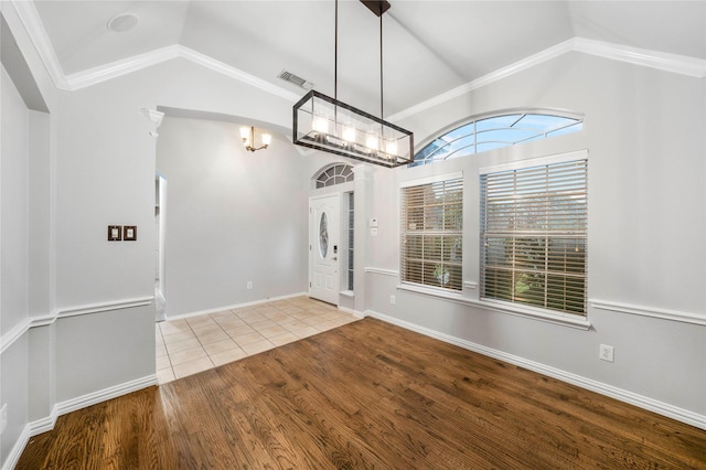 unfurnished dining area with visible vents, wood finished floors, baseboards, a chandelier, and vaulted ceiling