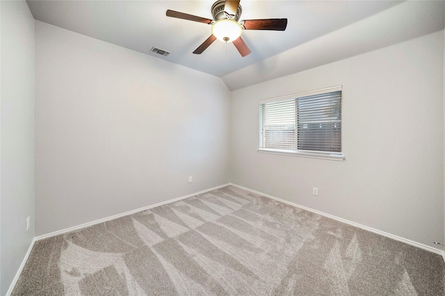 empty room featuring a ceiling fan, light colored carpet, visible vents, vaulted ceiling, and baseboards