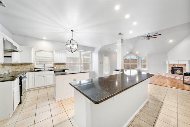 kitchen with stainless steel electric range, plenty of natural light, range hood, and a center island